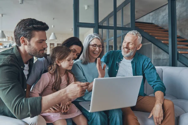 Família feliz usando laptop e sorrindo ao passar tempo em casa juntos — Fotografia de Stock