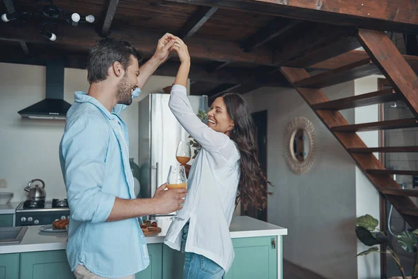 Gyönyörű fiatal pár mosolyog és táncol, miközben időt töltenek a konyhában. — Stock Fotó