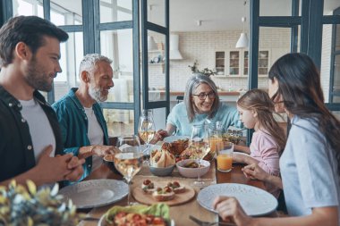 Birlikte yemek yerken gülümseyen çok nesilli aile.
