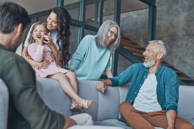 Mutlu bir aile birlikte vakit geçirir ve evdeki kanepede otururken gülümser.