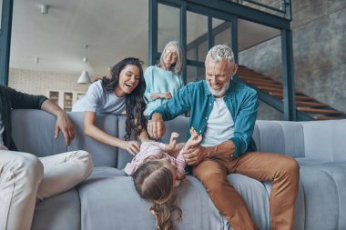 Mutlu bir aile birlikte vakit geçirir ve evdeki kanepede otururken gülümser.