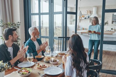 Birlikte yemek yerken gülümseyen çok nesilli aile.