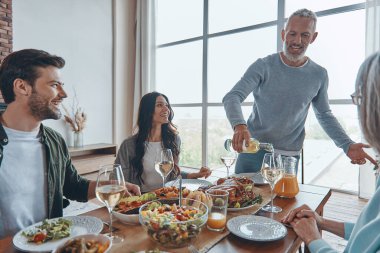 Mutlu çoklu nesil aile yemeği yerken iletişim kuruyor ve gülümsüyor.
