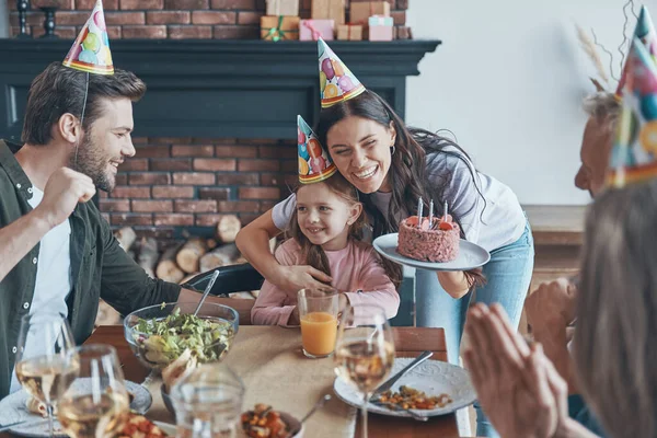 Família feliz comemorando aniversário da menina enquanto se senta na mesa de jantar em casa — Fotografia de Stock