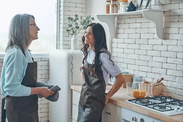Hermosa joven mujer y su madre comunicándose mientras pasa tiempo en la cocina doméstica — Foto de Stock