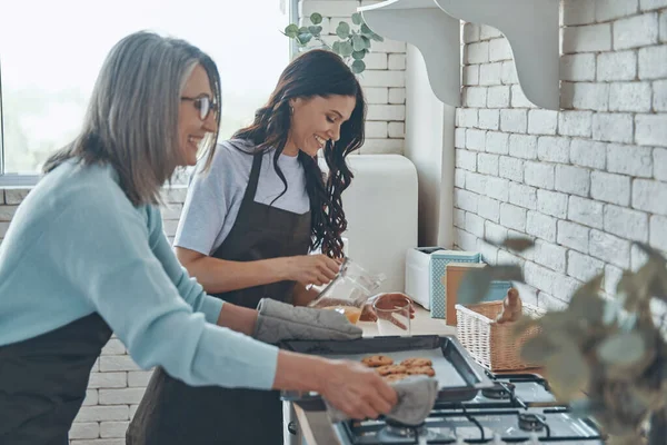 Güzel genç bir kadın ve annesi evcil mutfakta vakit geçirirken birlikte yemek pişiriyorlar. — Stok fotoğraf