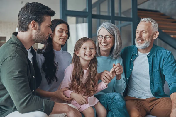 Feliz familia pasando tiempo juntos y sonriendo mientras están sentados en el sofá en casa —  Fotos de Stock