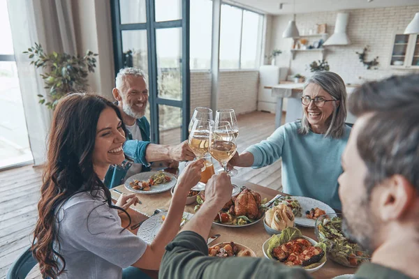Fröhliche Mehrgenerationenfamilie stößt beim gemeinsamen Essen an und lächelt — Stockfoto