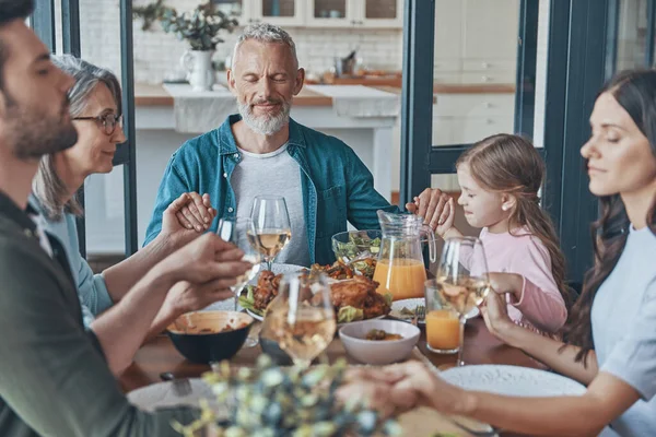 Gelukkige multi-generatie familie hand in hand en bidden voor het eten — Stockfoto