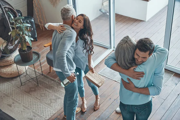 Draufsicht auf glückliche Senioren, die ein junges Paar im Haus treffen — Stockfoto