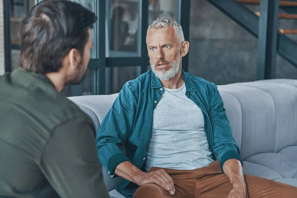 Jeune homme parlant à son père aîné tout en passant du temps à la maison ensemble — Photo