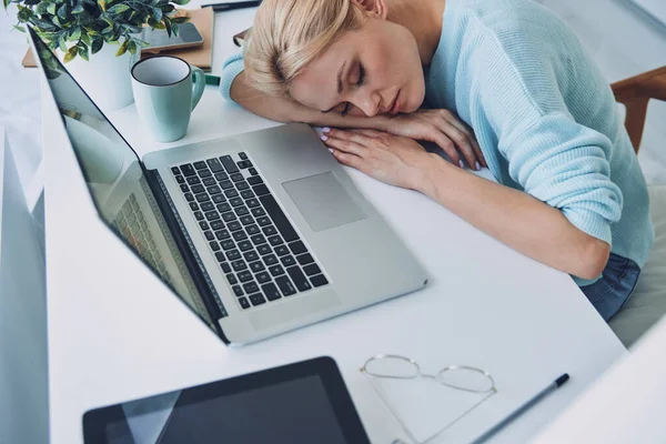 Visão superior da jovem cansada dormindo enquanto está sentada em seu local de trabalho no escritório — Fotografia de Stock