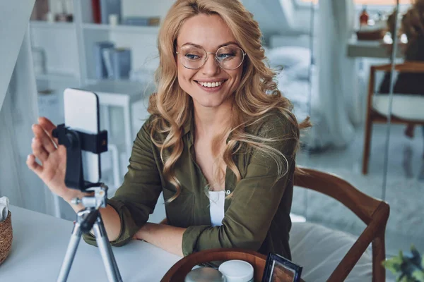Schöne junge lächelnde Frau vlogging, während sie im Home Office sitzt — Stockfoto