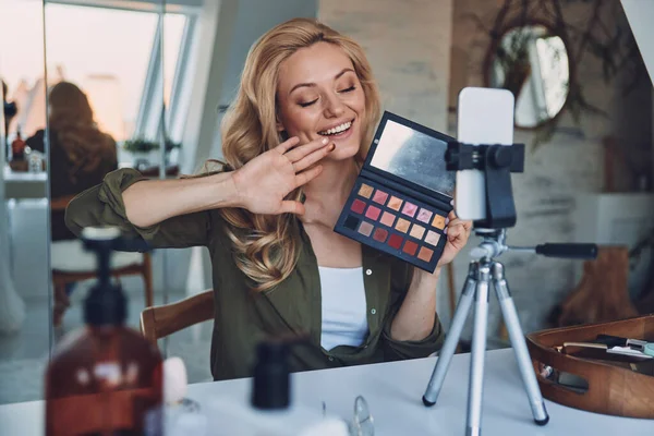 Atractiva joven sonriente mujer vlogging sobre maquillaje y productos de belleza —  Fotos de Stock