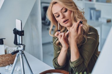 Makyaj ve güzellik ürünleri hakkında vloglayan çekici genç bir kadın.