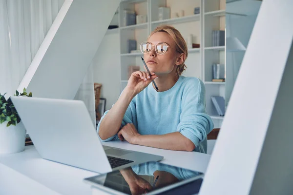 Gyönyörű fiatal nő használja laptop és néz figyelmes, miközben dolgozik az irodában — Stock Fotó