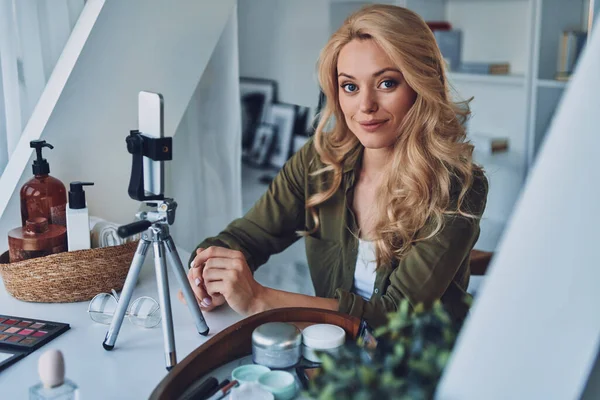 Gyönyörű fiatal mosolygós nő vlogging szépségápolási termékek és a kamera — Stock Fotó
