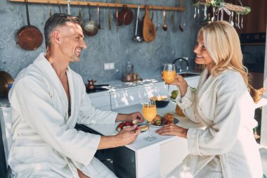 Evcil mutfakta vakit geçirirken bornozlu güzel bir çift kahvaltıdan zevk alıyor.