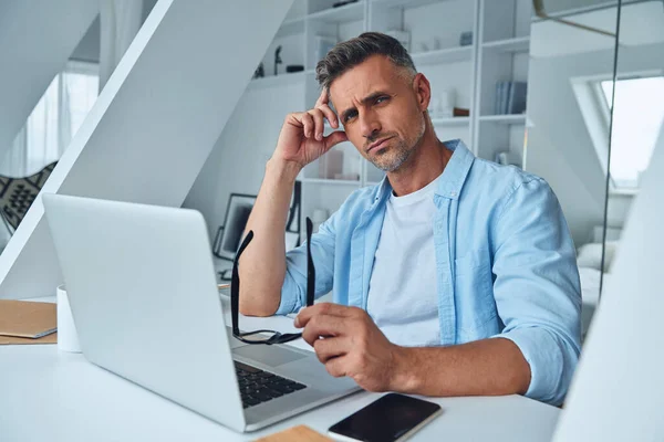 Homme mature confiant regardant la caméra alors qu'il était assis au bureau — Photo