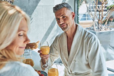 Evcil mutfakta vakit geçirirken bornozlu güzel bir çift kahvaltıdan zevk alıyor.