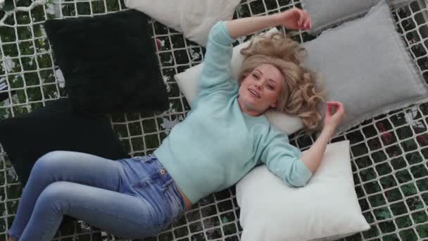 Visão superior da bela jovem mulher sorrindo enquanto relaxa na rede grande em casa — Vídeo de Stock