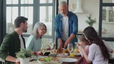 Son sınıf öğrencisi evde ailesiyle yemek yerken kızarmış tavuk kesiyor. 