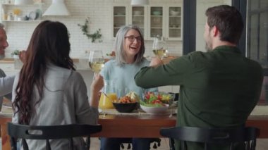 Mutlu çok nesilli aile yemeği yerken kadeh kaldırır ve gülümserler.