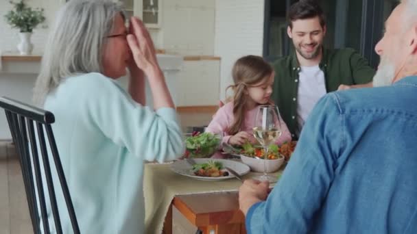 Keluarga multi-generasi yang bahagia bersulang dan tersenyum saat makan malam bersama — Stok Video