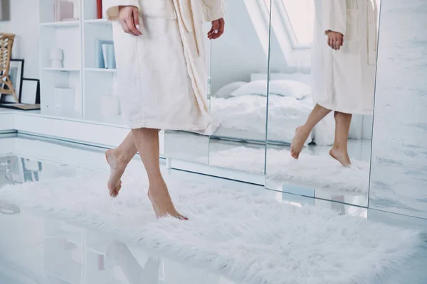 Primo piano della donna scalza che indossa accappatoio camminando davanti al grande specchio a casa — Foto Stock
