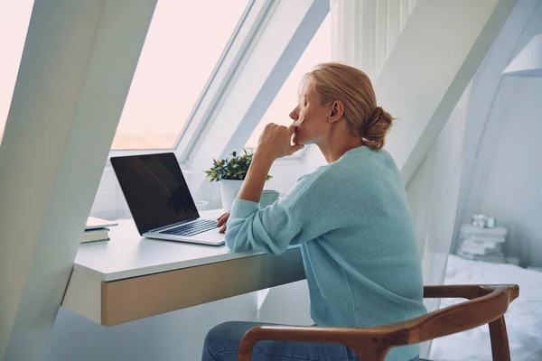 Schöne junge Frau benutzt Laptop, während sie zu Hause arbeitet — Stockfoto