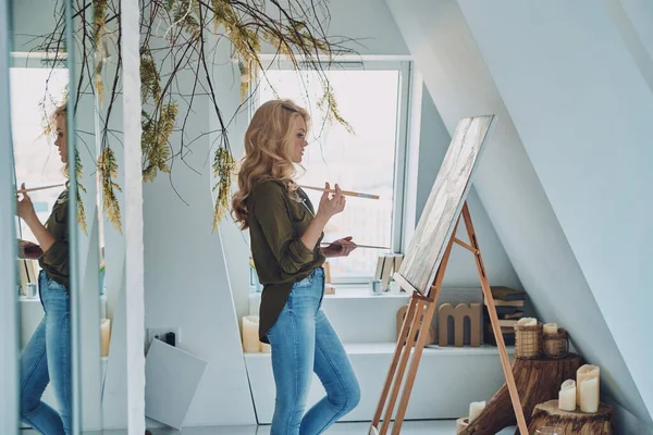 Widok z boku atrakcyjnej młodej kobiety malarstwo w studio sztuki — Zdjęcie stockowe