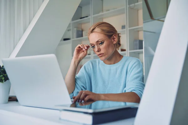 Gyönyörű fiatal nő használja laptop, miközben dolgozik az irodában — Stock Fotó