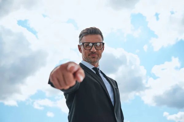 Low angle view of confident mature man in full suit pointing camera — Stock Photo, Image