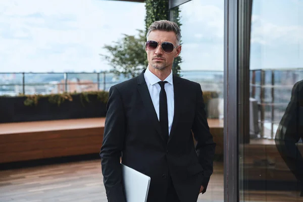 Zelfverzekerde volwassen man dragen laptop tijdens het lopen op het dakterras — Stockfoto