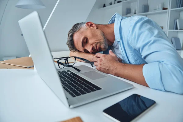 Trött mogen man sover när han sitter vid skrivbordet — Stockfoto