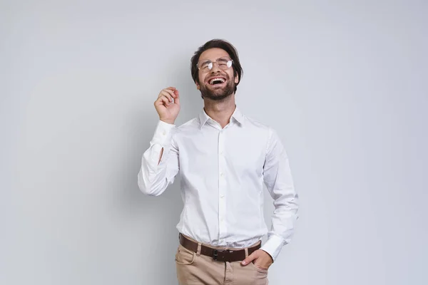 Knappe jongeman in wit shirt op zoek gelukkig terwijl staan tegen grijze achtergrond — Stockfoto
