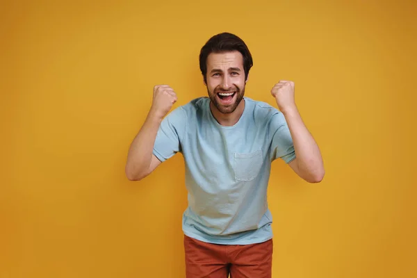 Jovem feliz em roupas casuais olhando para a câmera e gestos — Fotografia de Stock