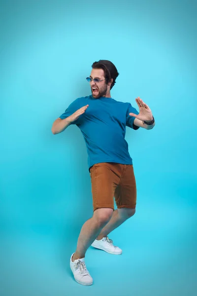 Spännande ung man i casual kläder gester när du står mot gul bakgrund — Stockfoto