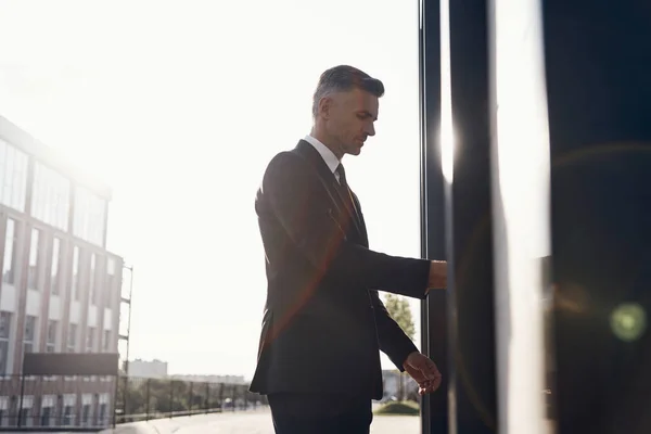 Confident mature businessman opening the door of business centre — Stock Photo, Image