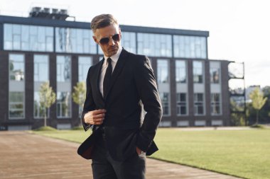 Ofis binasının önünde duran kendinden emin bir iş adamı.