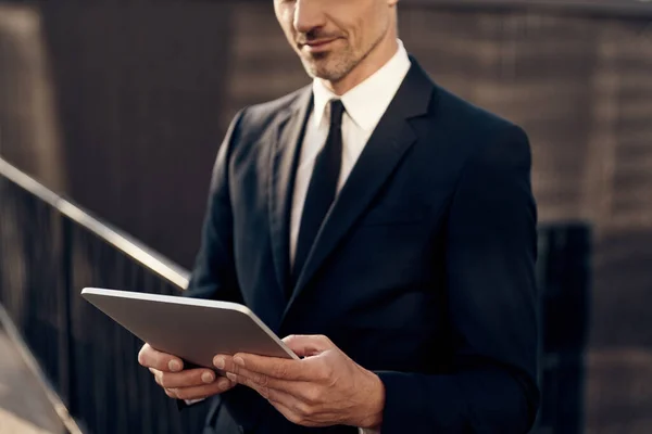 Close up of confident mature businessman working on digital tablet while standing outdoors — Stock fotografie