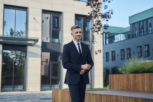 Fiducioso uomo d'affari maturo a piedi vicino edificio per uffici all'aperto — Foto Stock