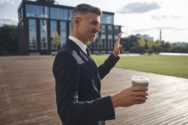 Empresário maduro confiante segurando xícara de café enquanto está perto do prédio de escritórios — Fotografia de Stock