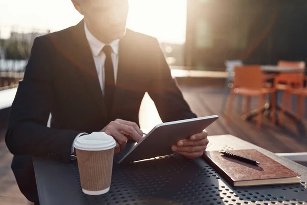 Концентрированный зрелый бизнесмен с помощью цифрового планшета, сидя в кафе на открытом воздухе — стоковое фото