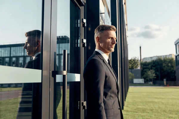 Confident mature businessman standing near office building outdoors — Stock Photo, Image