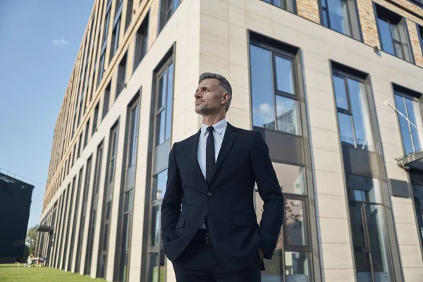 Впевнений зрілий бізнесмен стоїть перед офісною будівлею на відкритому повітрі — стокове фото