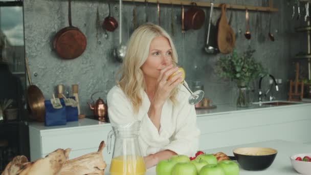 Schöne reife Frau in Bademänteln beim Frühstück in der heimischen Küche — Stockvideo