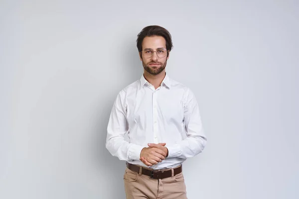 Hombre joven guapo en camisa blanca mirando a la cámara mientras está de pie sobre fondo gris —  Fotos de Stock