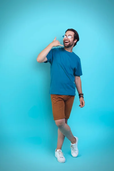 Handsome young man in casual clothing gesturing and smiling while standing against yellow background — Stock Photo, Image