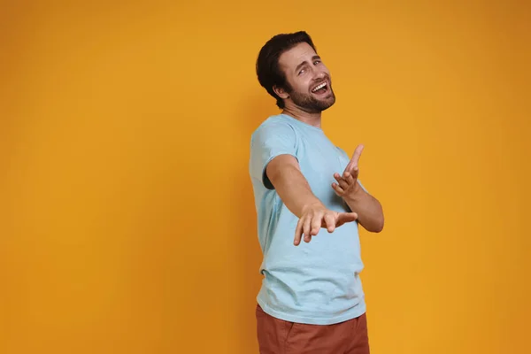 Gelukkig jongeman in casual kleding gebaren tegen gele achtergrond — Stockfoto